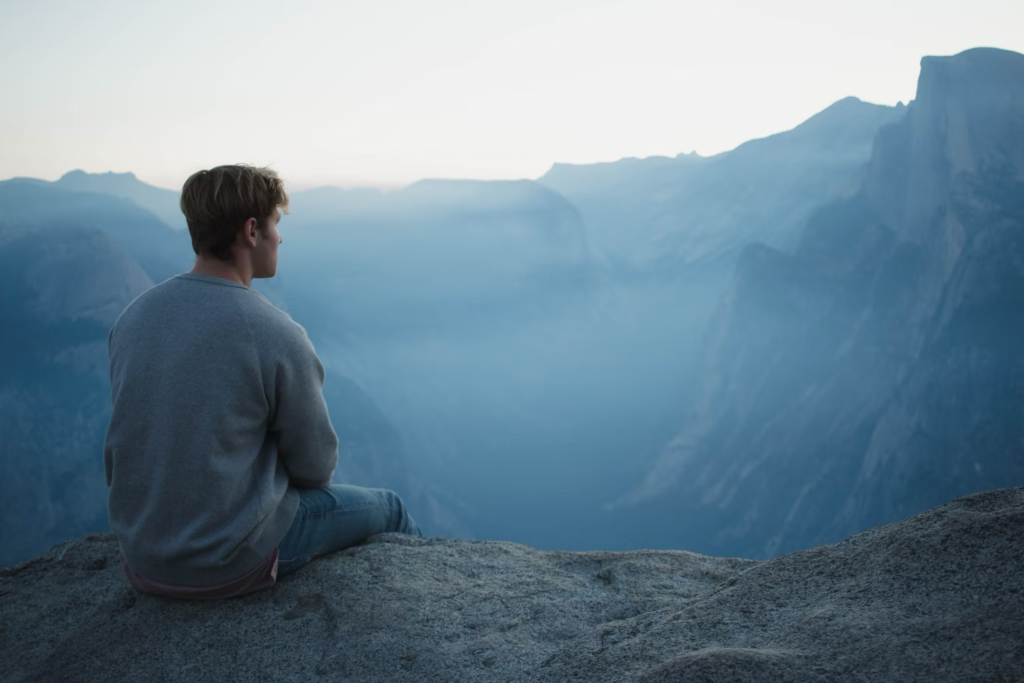  a man reflecting atop a mountain